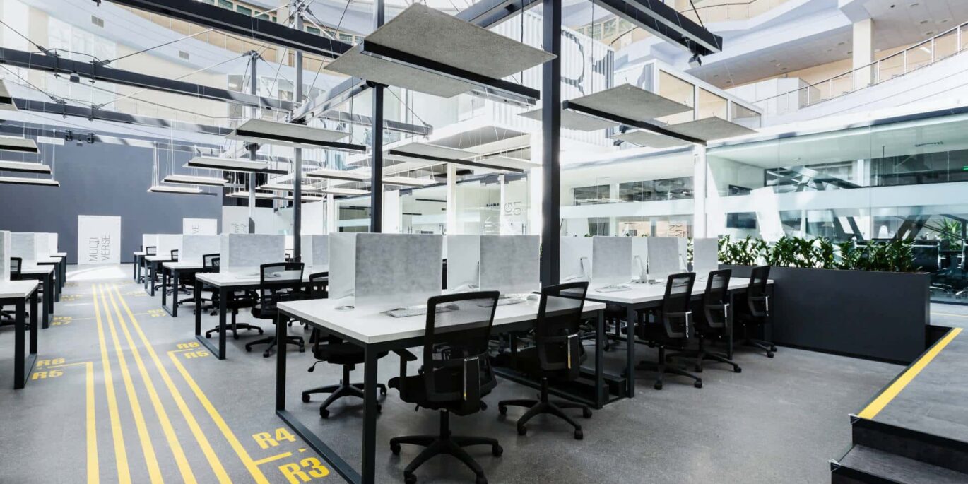 Großraumbüro mit modernen Schreibtischen, ergonomischen Stühlen und Sichtschutztrennwänden – Symbolbild für Büromöbel leasen.